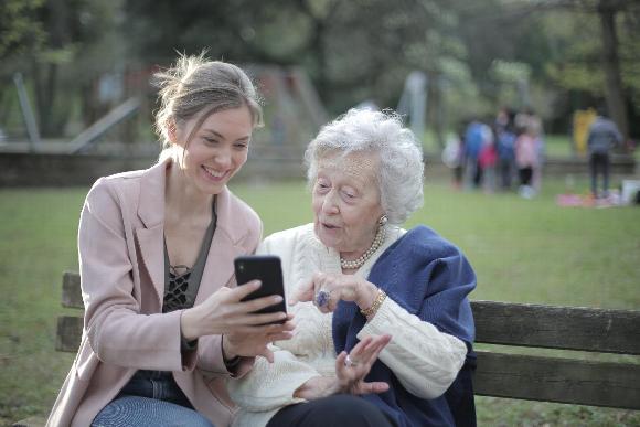 a lady showing her mobile phone to an elderly lady